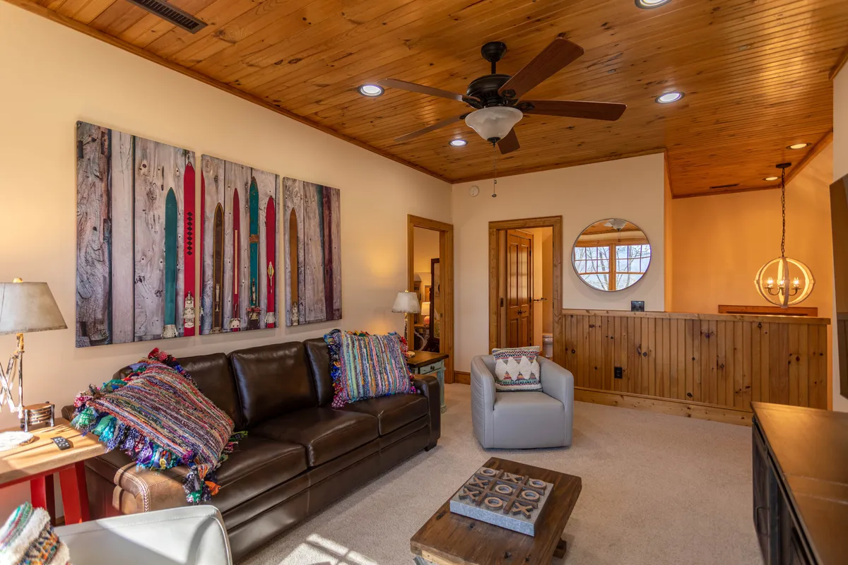 A warm, welcoming living area with a leather sofa, wooden coffee table, colorful wall art, and a ceiling fan. The layout is perfect for relaxing or socializing, and the vibrant artwork adds personality to the space.