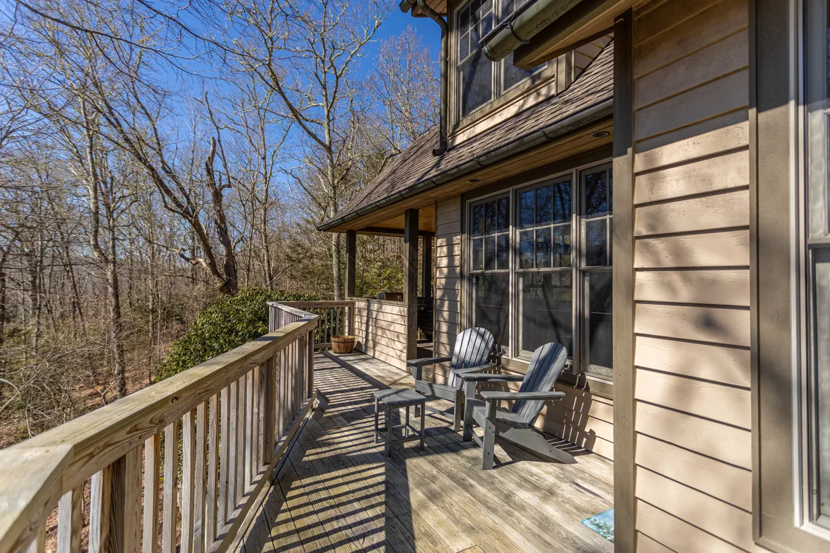 A serene wooden deck furnished with Adirondack chairs and surrounded by tall trees. The deck hints at relaxation, scenic views, and a seamless connection to the outdoors—making it perfect for guests and their dogs to enjoy together.